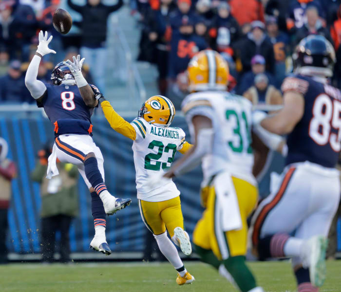 Jaire Alexander runs toward a Bears player as the ball is in the air